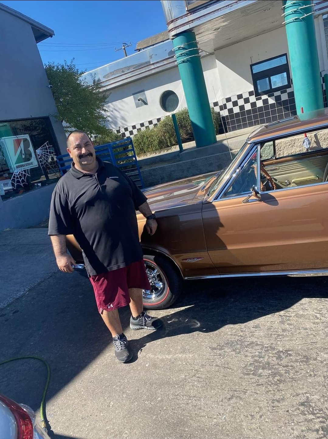 person standing next to muscle car